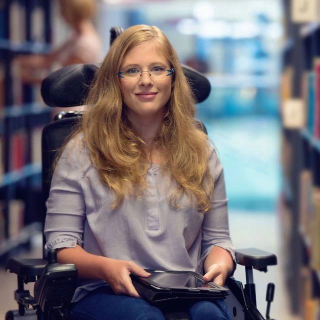 Frau mit Rollstuhl in Bibliothek