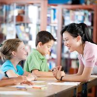 Lehrerin unterhält sich mit Schulkindern.
