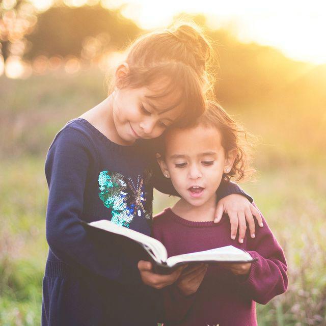 Zwei Schwestern lesen gemeinsam ein Buch.