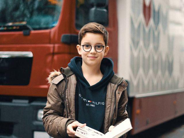 Ein Junge mit Buch steht vor dem Fahrzeug der Fahrbibliothek.