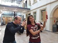 Ein Mitarbeiter der Stadtbibliothek fotografiert ein Buc,h, das von einer Kollegin gehalten wird.