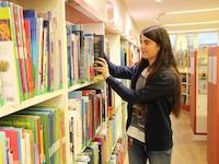 Eine Mitarbeiterin der Stadtbibliothek sortiert Bücher zurück ins Regal.